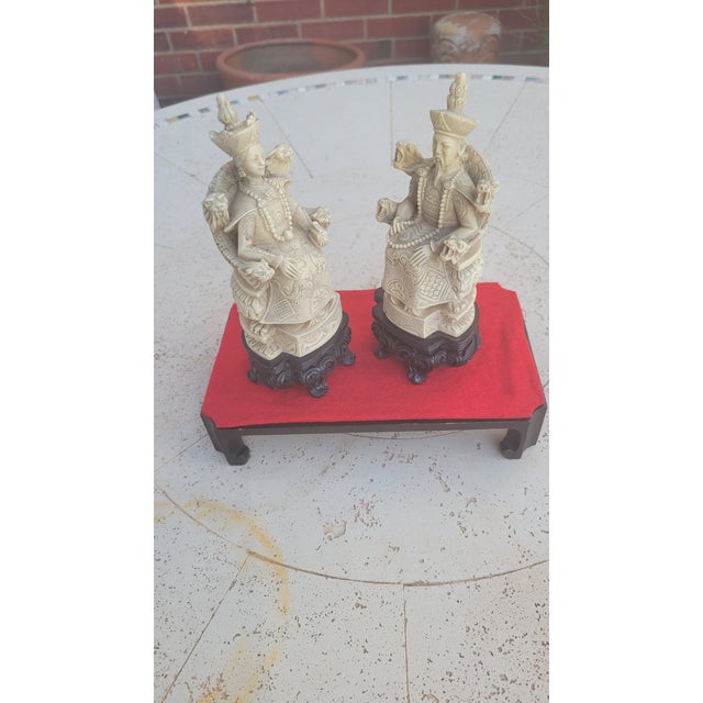 Vintage resin figurines depicting an emperor and empress sitting in thrones with vastly decorated court attire, including...