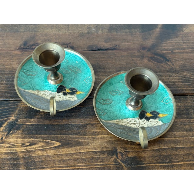 Pair of vintage enameled candlestick holders with a duck couple on a teal background. Most items found at Pub & Oasis are...