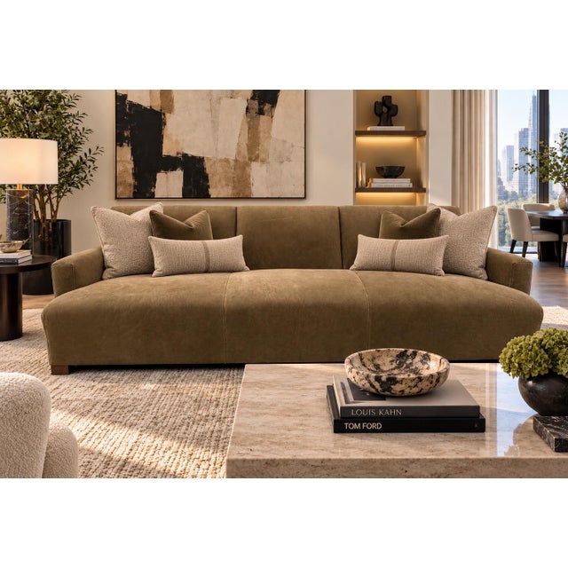 A contemporary three-seater sofa upholstered in a suede leather, featuring deep bench seating and sleek, low-profile...