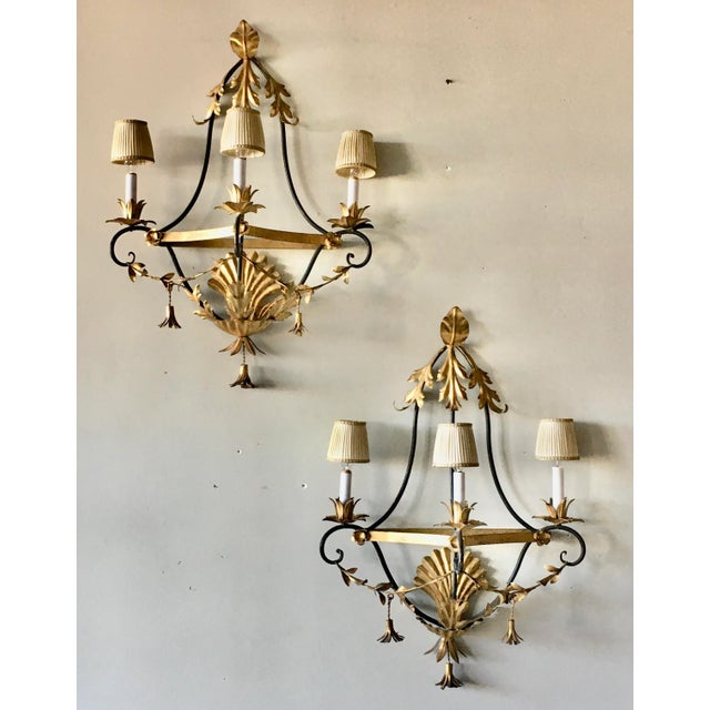 A pair of elegant tole sconce lights with silk shades. Made in Italy, tag. Gilded acanthus leaf, shell and tassel details....