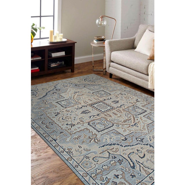 A hand-knotted wool rug in a traditional floral design, made in India and measuring 10' x 14'. Allover drawing held inside...