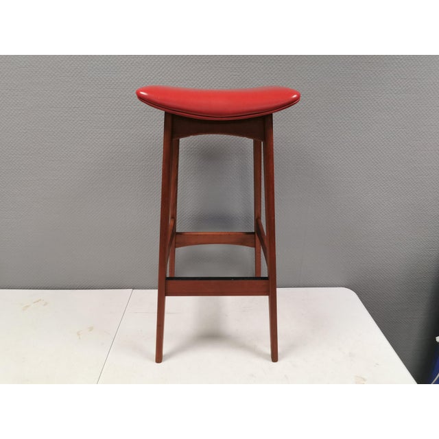 Extremely beautiful bar stool, made of teak wood and cognac/red leather. Designed by Johannes Andersen and produced at...