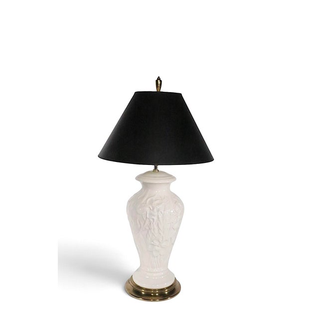 Decorative white ceramic table lamp having a raised foliate surface, mounted on a brass plinth. This example is in...