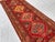 This antique hand-knotted Karabagh runner features four bold serrated diamond medallions in red, gold, and slate blue,...