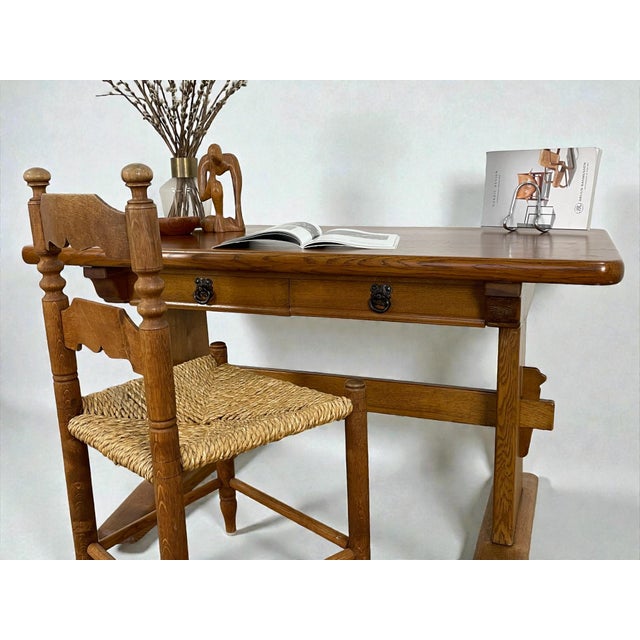 Danish writing desk crafted in oak, dating from circa the 1940s. The desk features a robust trestle base construction with...