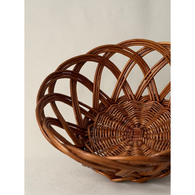 Hand-woven rattan basket with organic curved architecture. Tight weave base transitions to dramatic arching elements...