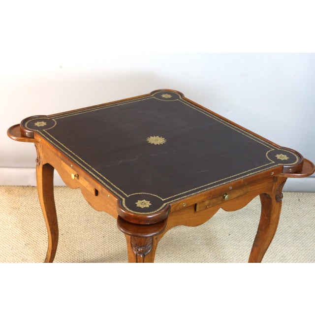 A carved and molded wooden games table, the frieze with four drawers and four token holders, the cabriole legs topped with...