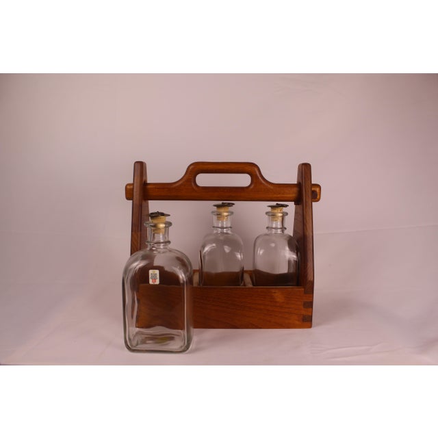 This is an antique bar caddy, made of a Danish teak with three glass decanter-like bottles. Formally known as a spirit...