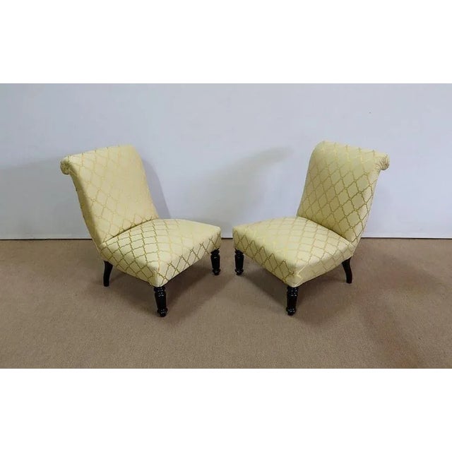 Charming pair of armchairs covered with a pastel yellow fabric decorated with golden arabesques and interlaced. These...