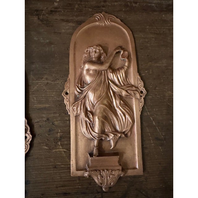 An evocative pair of antique French Art Nouveau copper-clad figural appliques, dating to circa 1880-1920. Each plaque...