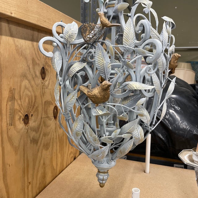 Heavy metal chandelier with a tangle of vines & leafs forming an oblong design intertwined with birds and a few metal bird...