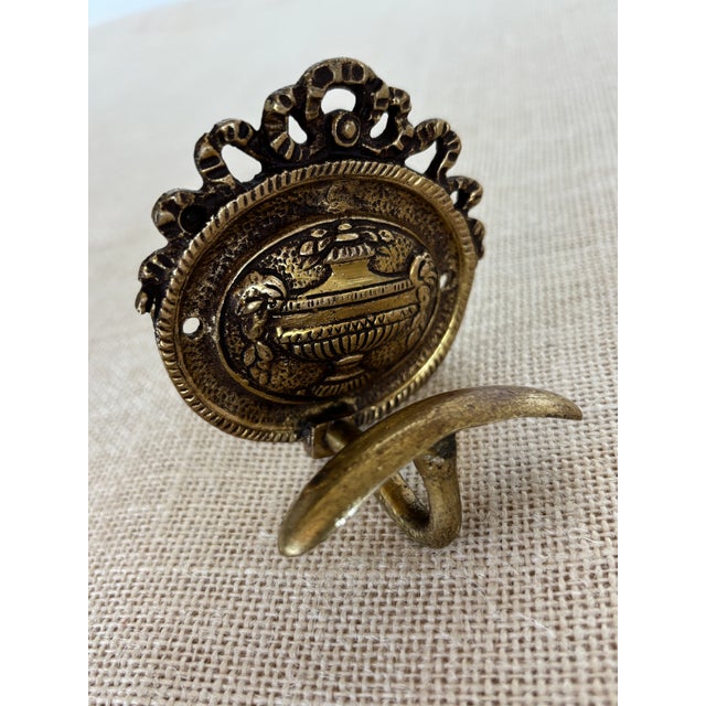 Antique Louis XVI style French cast brass Coat Hook with center Neoclassical urn motif surrounded with a rope trimmed oval...