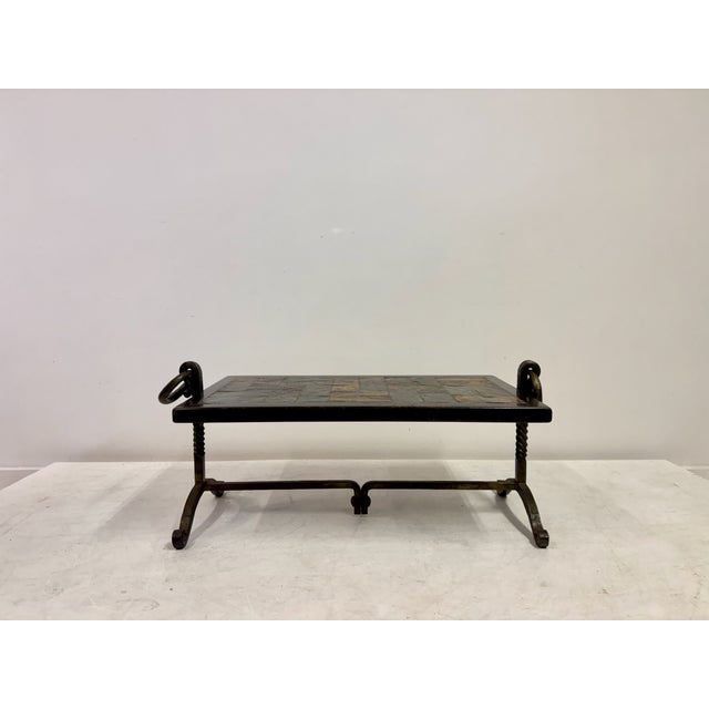 A low rectangular coffee table featuring a dark slate-tile top set within a black-stained wooden frame, raised on a...