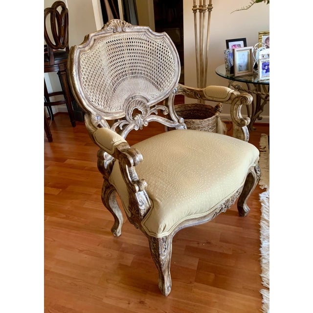Beautiful carved mindi wood arm chair with antiqued finish and silver accents. Back is cane. Seat is upholstered in...