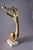 This sculpture reduces a musician to a single continuous gesture — one sweeping brass line running from an outstretched...