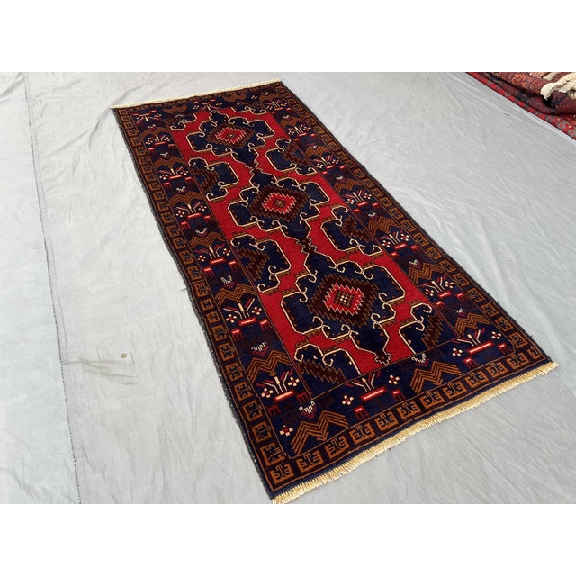 This hand-knotted Baluchi rug features bold geometric patterns in vibrant hues of red, blue, and yellow. The intricate...