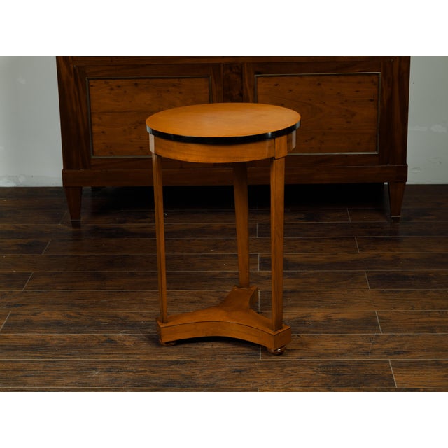 An Austrian Biedermeier period walnut guéridon table from the mid 19th century, with ebonized rim and lower shelf. Created...