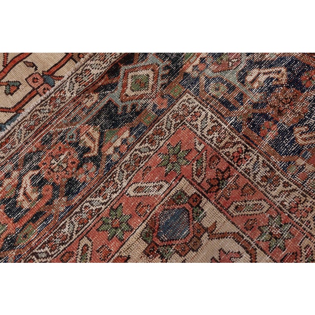 This antique Persian Heriz rug dating back to circa 1920 beautifully captures the essence of its mother-town...
