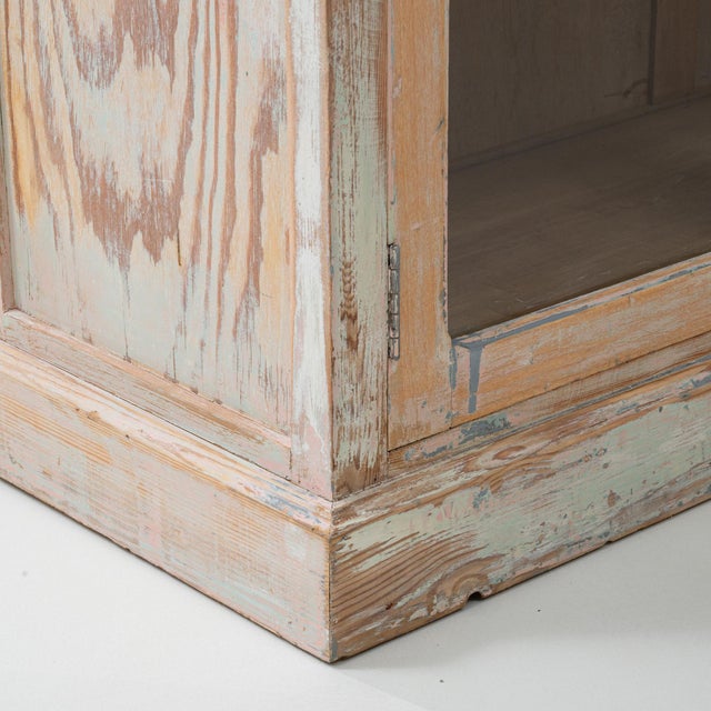 This 20th Century French wood patinated apothecary cabinet with glass doors is an impressive storage piece defined by its...