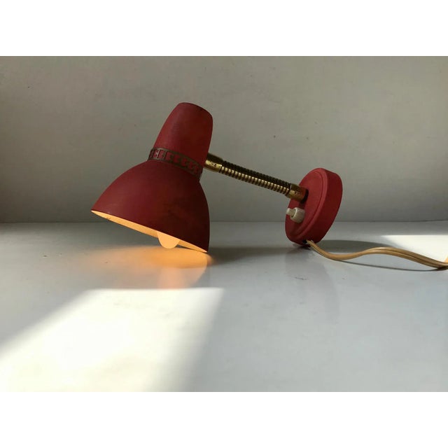 Adjustable wall lamp made from brass and aluminium. The pastel red lacquer has been applied in such a way that its surface...