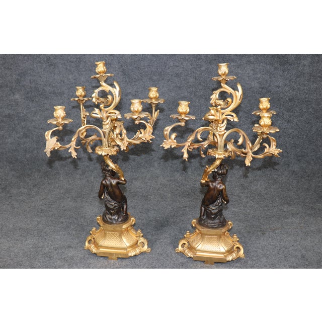 This magnificent French three-piece bronze and ormolu clock garniture, crafted during the late nineteenth century, is a...