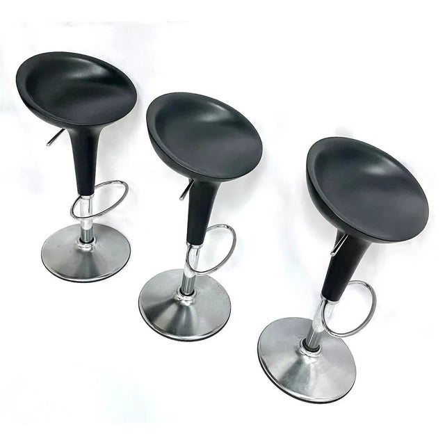 Set of three vintage molded plastic and brushed steel barstools with steel loop footrest and height adjustment lever that...