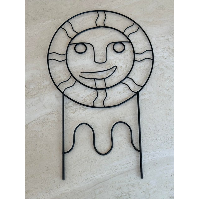 Elevate your space with this bold, sculptural Mid-Century Modern wire sun face, expertly crafted in sleek black metal. The...