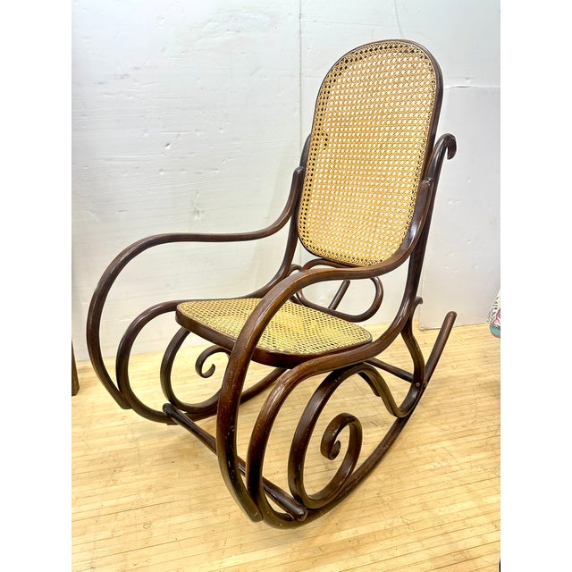 Authentic bentwood rocker with hand caned seat and back. Dark stained wood. Made in Poland, indicating Thonet produced