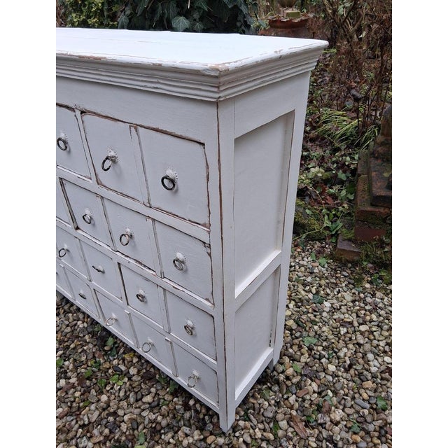A narrow wooden chest of drawers, beautifully shabby chic, with various signs of age and use. It's heavy, and the side...