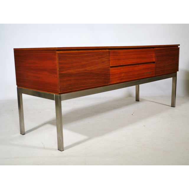 Mid-century modern audio lowboard/sideboard from the 1960s with a wooden cabinet and metal frame. The elongated body...