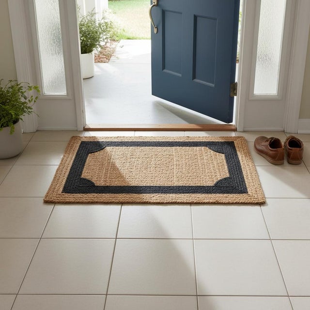 This handwoven jute rug showcases a timeless natural tone accented with a bold black border for a refined, modern look....