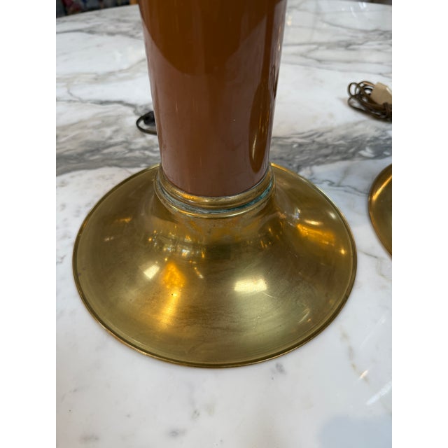 Elegant pair of mid-century modern table lamps featuring warm brass construction accented with rich brown lacquered...