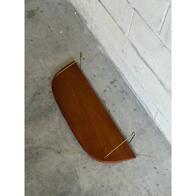 Beautiful vintage Danish wall shelf crafted in teak with elegant brass wire brackets. This minimalist Scandinavian...