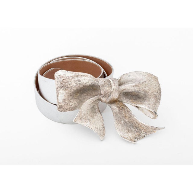 Christopher Ross Silvered Brass Bow Form Belt Buckle, 1985, signed and marked to reverse, together with a silver-tone belt...