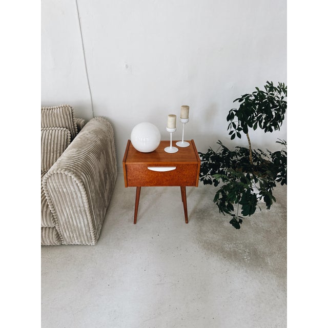 A beautiful pair of vintage 1960s Czech nightstands, featuring a striking burl wood veneer and classic mid-century modern...