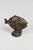 Cast bronze fish figurine with a dark patinated finish, raised circular eyes, geometric scale details, and a sculptural...