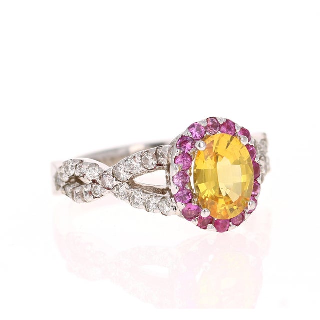 This ring has a 1.28 Carat Oval Cut Natural Yellow Sapphire. It has a halo of 17 Pink Sapphires that weigh 0.29 carats...