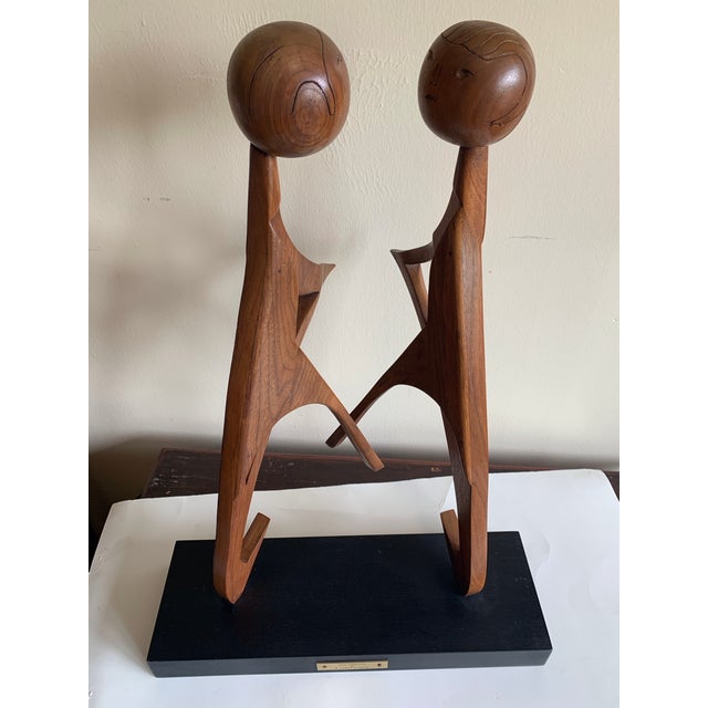 Mid 20th century teakwood abstract sculpture Love Embraced atop an ebonite’s wooden base. The two figures are attached to...