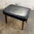 A vintage Danish modern stool from the 1960s with a black leather upholstered seat and tapered teak legs. The design is...