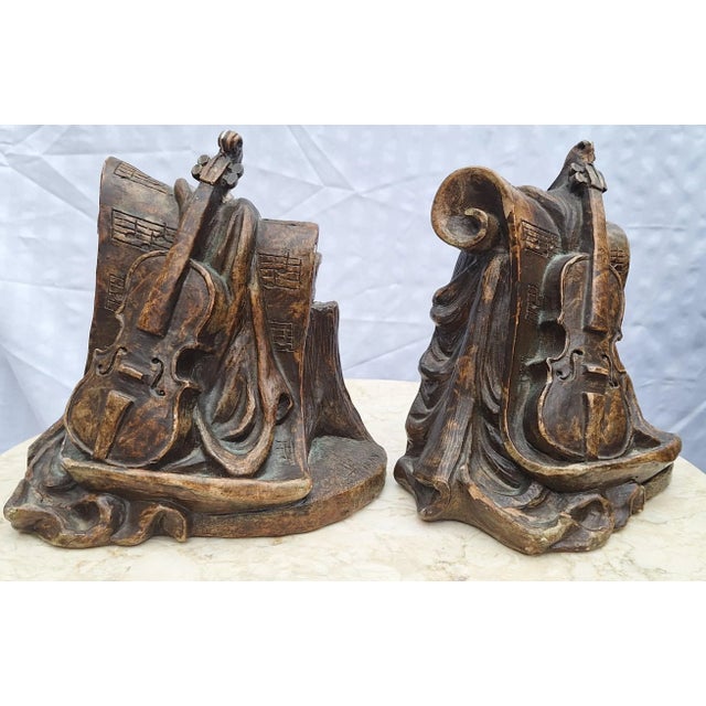 Presenting a pair of music motif bookends featuring the cello. Stringed instruments rest upon Trompe l'Oleil sheet music...