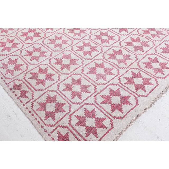 An Indian Agra reversible hand-knotted cotton rug dating back to circa 1930. It displays an all-over repeating pink flower...