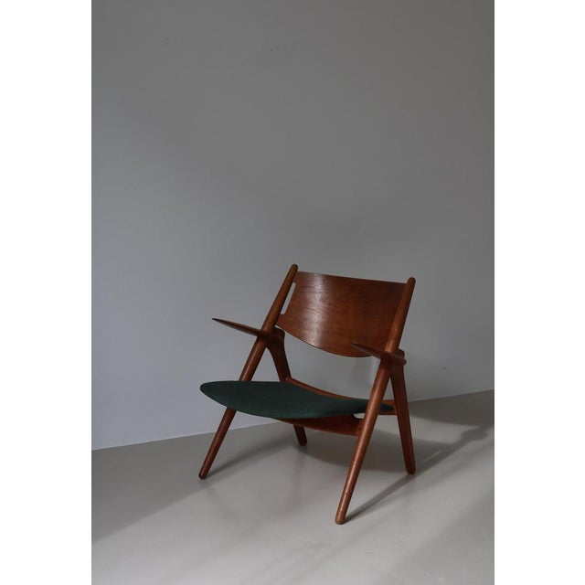Early production hans j. Wegner "ch28" lounge chair in patinated oak and dark green vintage upholstery. This example is...