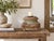 The front is a study in layers. Moldings stack one above the other, a band of scrolls and leaves sits at the center and a...
