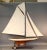 Wooden pond yacht with natural finish and painted white above the waterline. Linen sails, blue deck. 70" long x 11 1/2"...