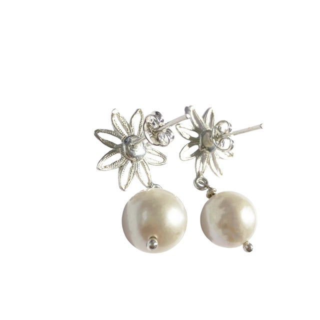 These custom-made earrings feature elegant round white pearls set in a filigree sterling silver design, resembling...