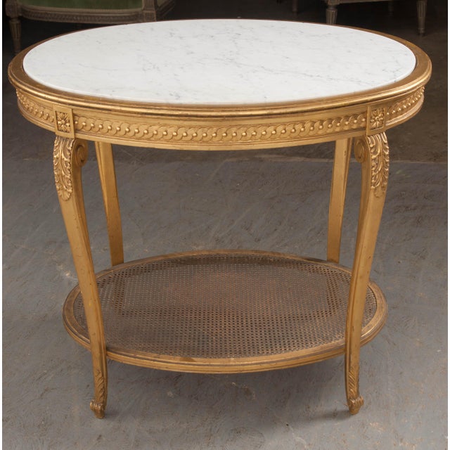 This graceful oval giltwood occasional table, circa 1880, was made in France and features a white marble top with delicate...