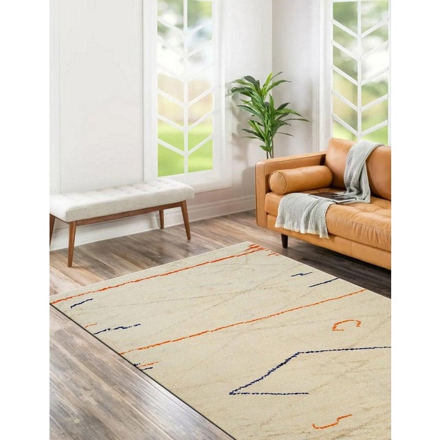 This hand knotted pile rug features a primary color palette of ivory, beige, cream, and white, offering a neutral...