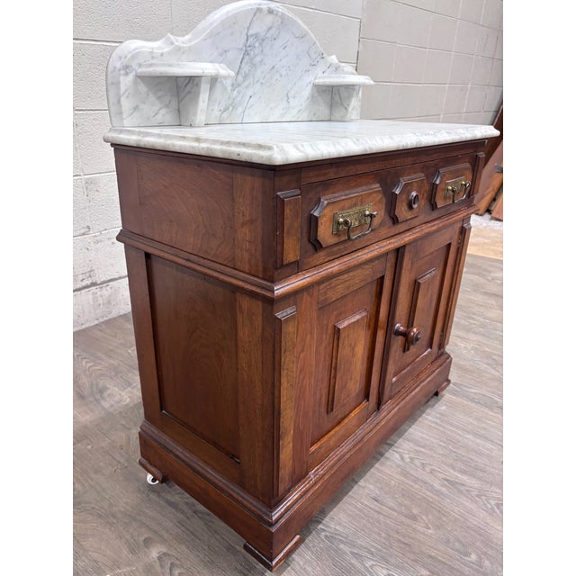 This is a gorgeous antique Victorian walnut marble-top washstand, circa 1870–1885, featuring an arched white marble...