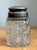 This antique vanity jar is a sophisticated example of early 20th-century personal grooming accessories, embodying the...