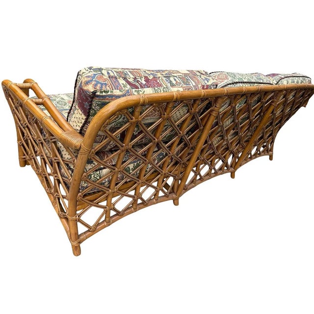 Description Coastal Classic three-seat rattan sofa featuring a warm honey-toned natural rattan frame with curved double-...